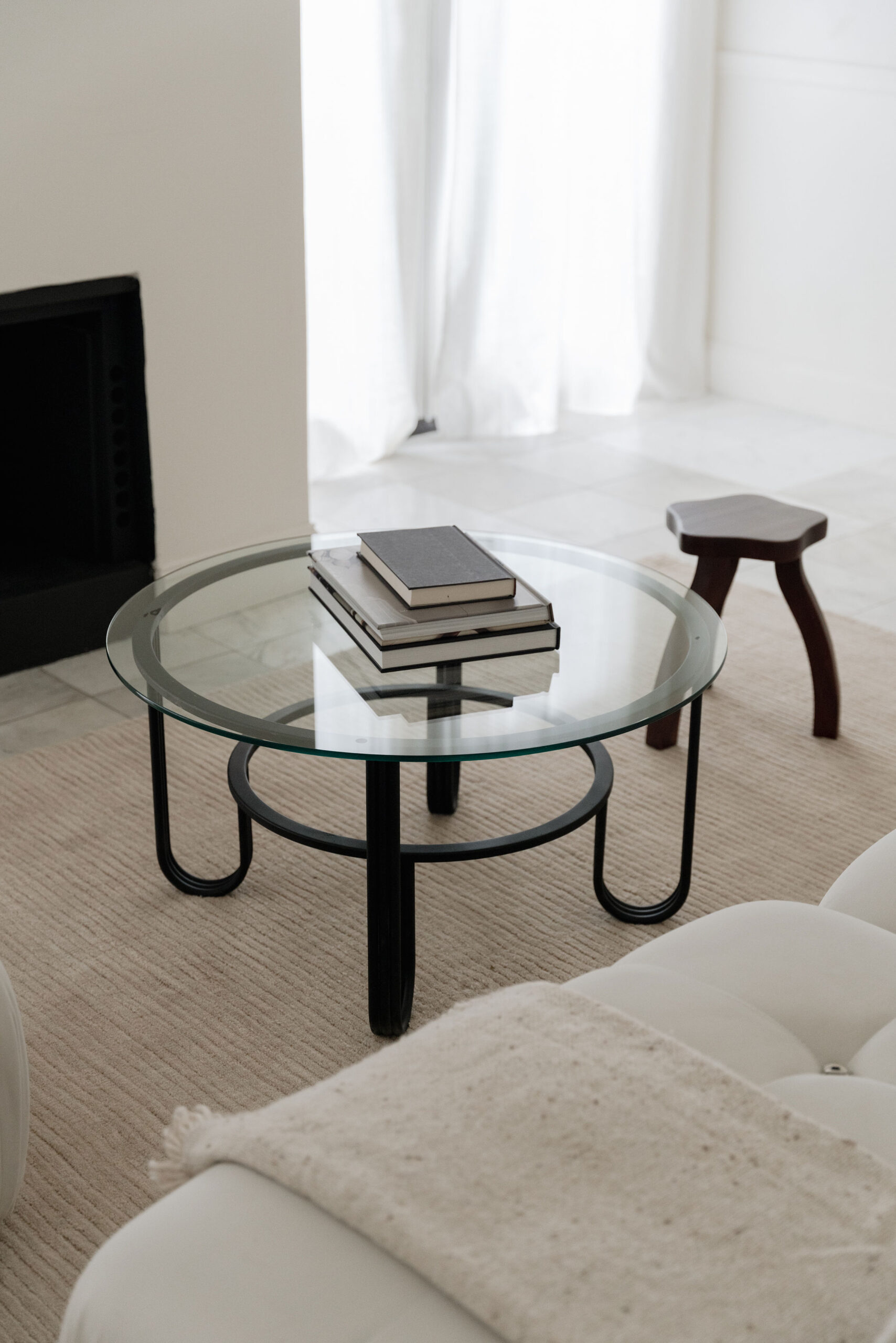 stack of books on a round glass coffee table with black metal legs
